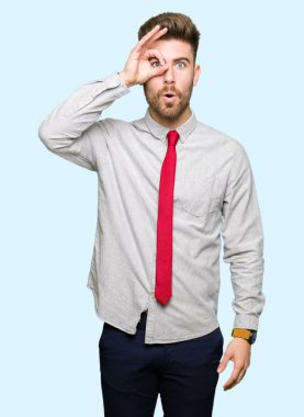 Genç yakışıklı iş adamı ok jest yapıyor sürpriz yüz, göz parmaklarının arasından seyir ile şok. İmansız ifade.