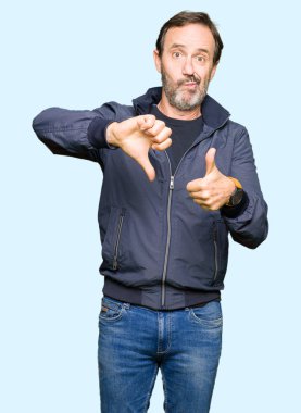 Orta yaş yakışıklı adam üzerinde bir ceket yapmak başparmak yukarı ve aşağı, anlaşmazlık ve anlaşma ifade. Deli çatışma