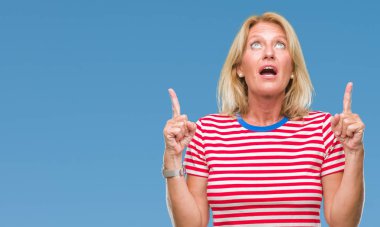 Orta yaş sarışın kadın izole arka plan üzerinden hayran ve yukarıya bakıp parmakları ile işaret şaşırttı ve silah kaldırdı.