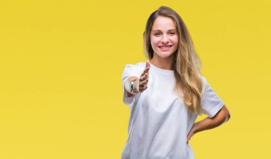 Tebrik ve konuksever dost sunan karşılıklı gülümseyen izole arka plan üzerinde rahat beyaz t-shirt giyen genç güzel sarışın bir kadın. Başarılı iş.