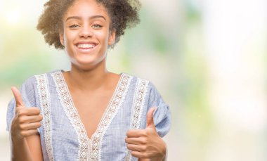 İzole arka plan başarı işareti el ile olumlu hareketi yaparken Genç afro Amerikan kadın başparmak gülümseyen ve mutlu. Neşeli bir ifadeyle, kazanan jest kameraya bakıyor.