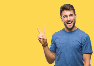 Mutlu yüz zafer işareti yaparken kameraya göz kırpıyor ile gülümseyen izole arka plan üzerinde genç yakışıklı adam. İki numaralı.