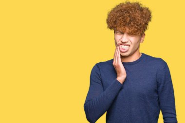 Diş ağrısı veya dişlerde dişlerle ilgili hastalık nedeniyle ağız acı ifadesi ile el ile dokunmak afro saçlı Genç yakışıklı adam. Diş hekimi kavramı.
