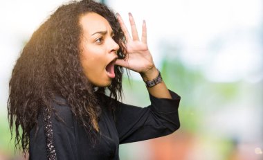 Kıvırcık saçlı bağırarak ve ağzı üzerinde el ile yan için çığlık zarif elbise genç güzel kız. İletişim kavramı.