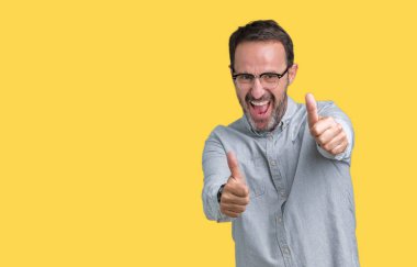 El ile pozitif jest yapıyor onaylama izole arka plan üzerinde gözlük takan yakışıklı orta yaş zarif komuta sizde başparmak gülümseyen ve başarı için mutlu. Kamera, kazanan jest arıyorsunuz.