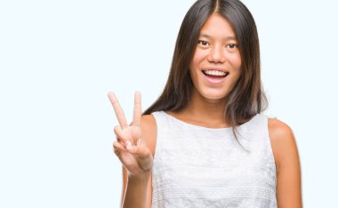 Genç Asyalı kadın mutlu yüz zafer işareti yaparken kameraya göz kırpıyor ile gülümseyen izole arka plan üzerinde. İki numaralı.