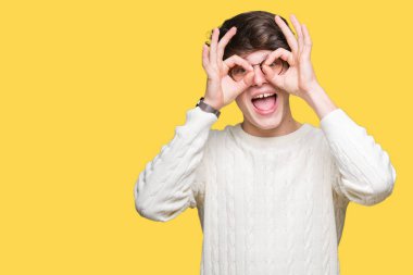 Dilini, parmaklarının arasından baktığını yapışmasını dürbün gibi ok jest yapıyor izole arka plan üzerinde gözlük takan yakışıklı delikanlı. Deli ifade.