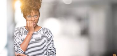 Stresli ve gergin elle çivi ısırma ağzına bakarak izole arka plan üzerinde gözlük güzel genç Afro-Amerikan kadın. Anksiyete sorunu.