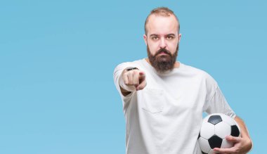 Genç beyaz hipster adam futbol futbol topu tutan kamera ve size parmak ile işaret arka plan izole, el işareti, pozitif ve kendinden emin bir jest ön