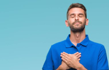 Yakışıklı delikanlı ile gülümseyen izole arka plan üzerinde kapalı gözler ve yüzünde minnettar jest ile göğüs üzerinde eller. Sağlık kavramı.