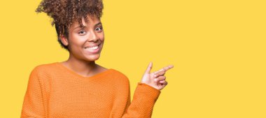 Yüzünde kocaman bir gülümseme ile izole arka plan üzerinde güzel genç Afro-Amerikan kadın kameraya bakarak yan el ve parmak ile işaret.