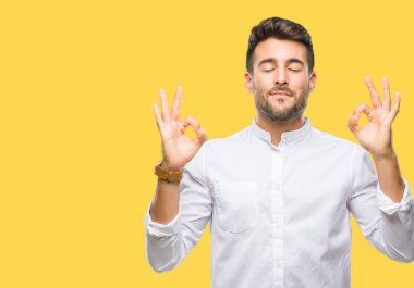 Yakışıklı delikanlı izole arka plan üzerinde dinlenmek ve gülümseyen gözlerle parmak ile meditasyon jest yapıyor kapalı. Yoga kavramı.