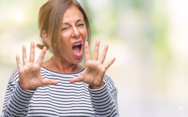 Şokta bağırarak orta yaş üst düzey İspanyol kadın izole arka plan korkuyor ve korku ifade dur hareketi el ile ile çok korkmuş. Panik kavramı.