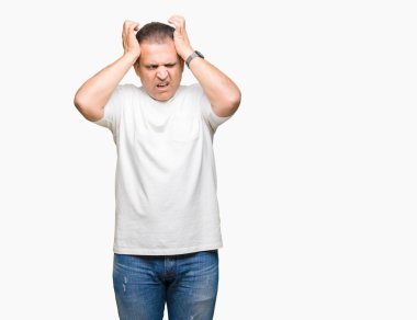 Orta yaş Arap adam wearig beyaz t-shirt çünkü umutsuz ve stresli baş ağrısı acı izole arka plan üzerinde ağrı ve migren. Ellerini kafasına.