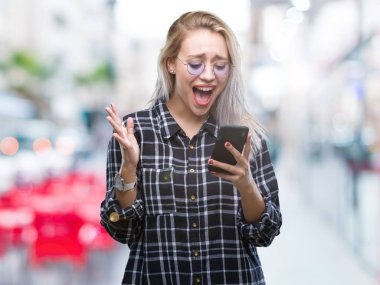 Sarışın genç kadın manifatura üzerinden Smartphone kullanarak ileti gönderme büyük gülümseme ile çığlık zaferini kutluyor ve ellerini kaldırdı arka plan çok mutlu ve heyecanlı, kazanan ifade izole