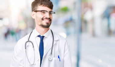 Genç izole arka plan uzak tarafına gülümseme ile yüzünde, doğal ifade bakmaktan hastane ceket giyen adam doktor. Kendine güvenen gülüyor.