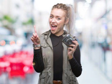 Sarışın genç kadın üzerinde Vintage kamera ile fotoğraf çekimi arka plan ile bir fikir ya da gülen yüz, bir numara ile parmak işaret soru sürpriz izole