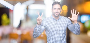 Yakışıklı delikanlı gösterilen ve parmakları ile işaret izole arka plan üzerinde kendinden emin ve mutlu gülümseyerek süre yedi numara.