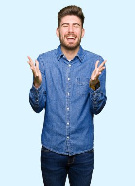 Genç yakışıklı sarışın adam rahat kot gömlek kızgın ve silah ile başarı için deli kutluyor giyen kaldırdı ve heyecanlı çığlık gözler kapalı. Kazanan kavramı