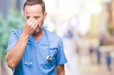 Orta yaş ağarmış kıdemli Doktor izole arka plan yorgun sürtünme burun ve göz yorgunluğu ve baş ağrısı duygu üzerinde tıbbi üniforma giyen adam. Stres ve hayal kırıklığı kavramı.