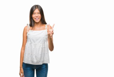 Genç Asyalı kadın mutlu yüz zafer işareti yaparken kameraya göz kırpıyor ile gülümseyen izole arka plan üzerinde. İki numaralı.