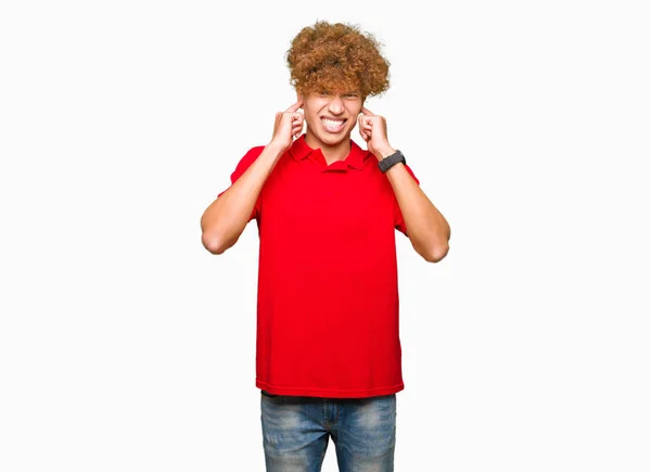 騒々しい音楽のノイズの腹が立つ式の指で赤い シャツ カバー耳を着てアフロの髪の若いハンサムな男 聴覚障害者の概念 — ストック写真
