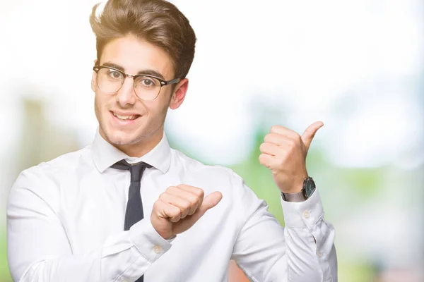 若いビジネス人にメガネをかけて背景を分離した自信の笑みを浮かべて手と親指 裏側を指す — ストック写真