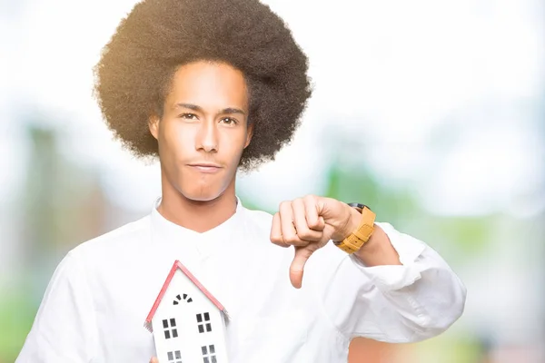 怒った顔 ダウン親指で嫌悪感を示すマイナス記号 拒絶反応の概念と家を保持してアフロの髪の若いアフリカ系アメリカ人 — ストック写真