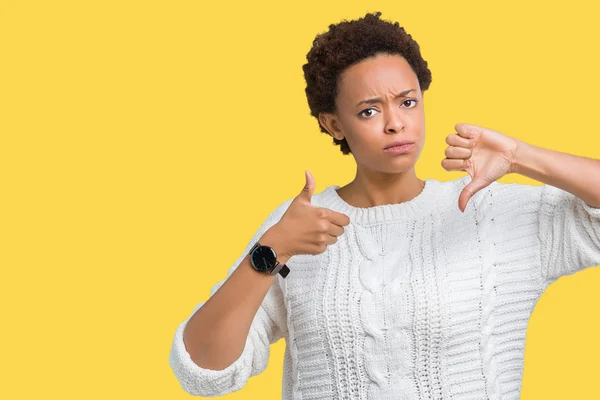 Beautiful young african american woman wearing sweater over isolated background Doing thumbs up and down, disagreement and agreement expression. Crazy conflict