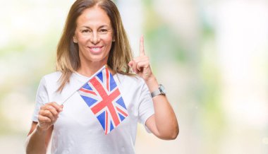Bir fikir ya da soru işaret parmağı ile gülen yüz, bir numara büyük Britanya bayrağı izole arka plan üzerinde tutan orta yaş İspanyol kadın şaşırttı