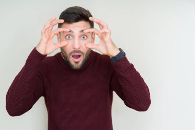 Parmaklarıyla, Uykulu ve sabah yorgunluk için yorgun gözlerini açmaya çalışırken izole arka plan üzerinde bir kazak giyen genç yakışıklı adam