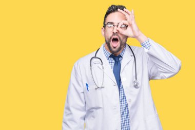 Sürpriz yüz, göz parmaklarının arasından seyir ile ok jest yapıyor izole arka plan yakışıklı genç doktor adam şok. İmansız ifade.