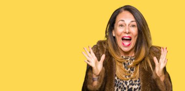 Vizon ceket kutluyor giyen güzel orta yaş zarif kadın şaşırttı ve başarı için kaldırdı kollarını açarak hayret ve gözleri açık. Kazanan kavramı.