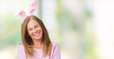 Paskalya tavşan kulakları üzerinde giyen orta yaş esmer kadın arka plan ile mutlu yüz gülümseyerek kameraya seyir silah geçti izole. Olumlu bir kişi.