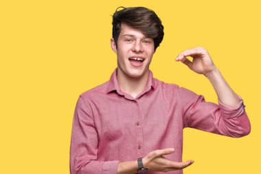 Genç yakışıklı iş adamı izole arka plan eller eller büyük gösterilen ve büyük boy işareti, ölçü birimi sembolü ile üzerinden. Kameraya bakarak gülümsüyordu. Ölçüm kavramı.