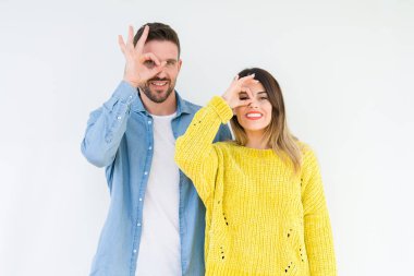 Genç güzel çift togheter gülümseyen, parmakları ile mutlu yüz üzerinden seyir göz el ile ok jest yapıyor izole arka plan üzerinde.