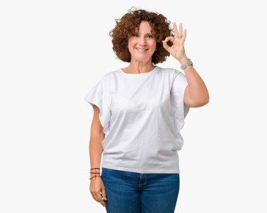 İzole arka plan el ve parmaklar ok işaretiyle yapıyor olumlu gülümseyen üzerinde beyaz t-shirt giyen güzel orta ager kadın kıdemli. Başarılı ifade.