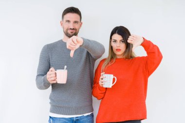 Kızgın yüz, eksi işareti aşağı antipati başparmak ile gösterilen, ret kavramı ile izole arka plan üzerinde kahve içme genç çift