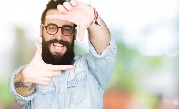 年轻的嬉皮士男子长头发和胡子戴着眼镜微笑的框架与手和手指与快乐的脸 创意和摄影理念 — 图库照片