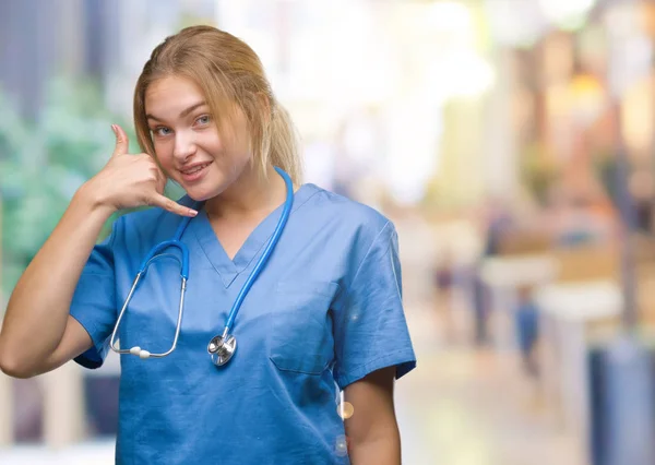 年轻的高加索医生妇女穿着外科医生制服在孤立的背景微笑着做电话手势用手和手指喜欢在电话里说话 传达概念 — 图库照片