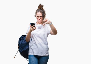 Sırt çantası, kulaklık ve akıllı telefon üzerinde giyen genç esmer öğrenci kız arka plan kızgın yüzü, eksi işareti aşağı antipati başparmak ile gösterilen, ret kavramı ile izole