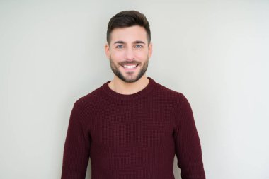 Yakışıklı delikanlı üzerinde izole arka plan ile bir mutlu ve güzel bir kazak giyen yüzündeki gülümseme. Şanslı kişi.