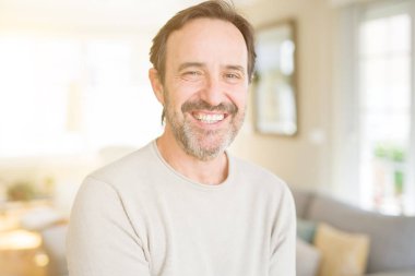 Evde kameraya bakarak gülümseyen yakışıklı orta yaş erkek