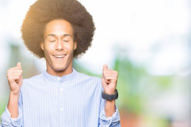 Silah ile başarı için heyecanlı afro saçlı genç Afro-Amerikan adam zafer kutluyor gülümseyen kaldırdı. Kazanan kavramı.