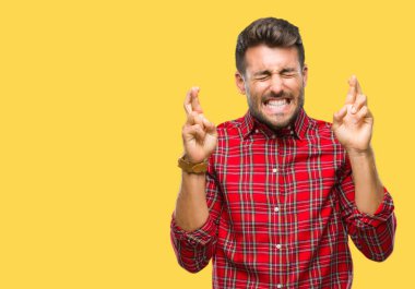 Yakışıklı delikanlı geçiş parmakları umut ve gözleri kapalı ile gülümseyen izole arka plan üzerinde. Şans ve batıl kavramı.