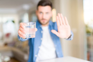 Yakışıklı delikanlı ile evde su içme dur işareti ile ciddi ve kendine güvenen ifade, savunma hareketi yaparken el açmak