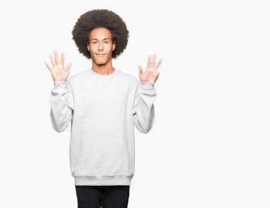 Afro saçlı kadar sportif kazak gösterme ve işaret parmakları ile giyen genç Afro-Amerikan adam numara 9 kendinden emin ve mutlu gülümseyerek süre.