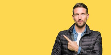 Yakışıklı adam giyen kış reklam, ciddi ve sakin yüz gösterilen yan el parmak ile işaret kat