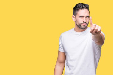 Yakışıklı adam izole sarı üzerinde beyaz t-shirt giyen işaret parmağını ve kızgın ifade ile arka plan