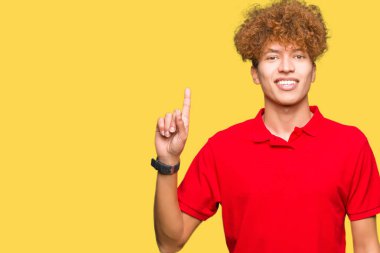 Gösterilen ve kendinden emin ve mutlu gülümseyen bir parmak ile işaret eden oktan yukarı kırmızı t-shirt giyen afro saçlı Genç yakışıklı adam.